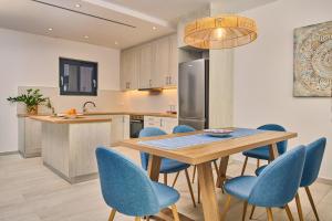 a kitchen with a wooden table and blue chairs at Sea Front Zante Apartments in Zakynthos Town