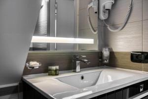 baño con lavabo blanco grande y luz en Operà Suites Pinciana, en Roma