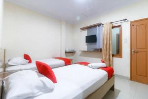 TanjungjohorにあるRedDoorz Plus near WTC Batanghari Mallの赤をアクセントにしたベッド2台が備わる客室です。