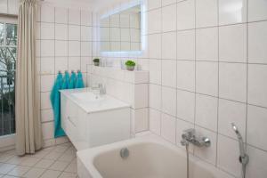 La salle de bains blanche est pourvue d'une baignoire et d'un lavabo. dans l'établissement Haus mit 110qm und Garten 150m zum Wasser, à Stralsund