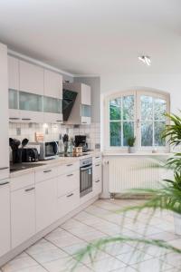 una cucina bianca con armadi bianchi e una finestra di Haus mit 110qm und Garten 150m zum Wasser a Stralsund