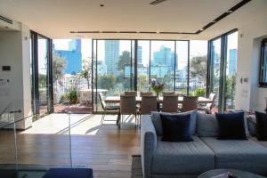 ein Wohnzimmer mit einem Sofa und einem Tisch mit Stühlen in der Unterkunft 4BDR - Stunning & Magnificent Duplex Penthouse TLV in Tel Aviv