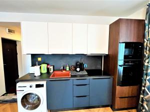 a kitchen with white cabinets and a washing machine at Bravo 5 Holiday Home in Sunny Beach