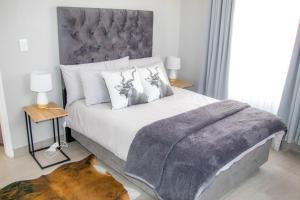 a bedroom with a bed with a grey blanket on it at Ongwe Leisure Property in Swakopmund