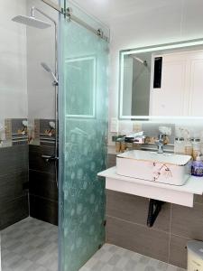 uma casa de banho com uma cabina de duche em vidro e um lavatório. em Phụng Hoàng Vũ em Bạc Liêu