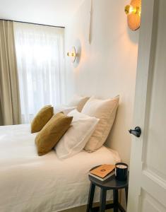 um quarto com uma cama com almofadas brancas e uma janela em La Porte Rouge - The Red Door em Oudenaarde