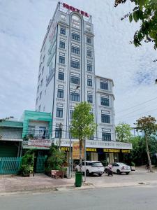 un edificio blanco alto con coches estacionados frente a él en Phụng Hoàng Vũ, en Bạc Liêu