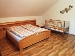 a bedroom with a crib and a wooden floor at Ferienwohnung Steiner Gertrude in Gaming