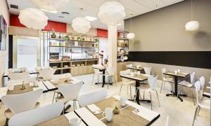 a restaurant with tables and white chairs and a counter at Sercotel Togumar in Madrid