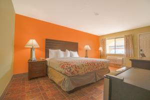 1 dormitorio con 1 cama con pared de color naranja en Aransas Bay Inn & Suites Corpus Christi by OYO en Aransas Pass