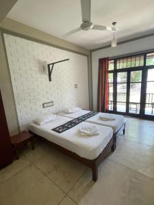 a bedroom with two beds and a clock on the wall at Serein Beach Hotel in Tangalle