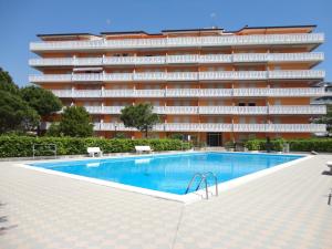 a swimming pool in front of a large building at Homely flat with shared pool in Porto Santa Margherita di Caorle