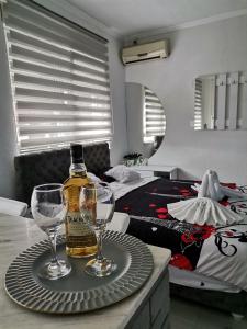 a bottle of alcohol on a tray with two wine glasses at Apartman u centru in Šid
