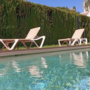two lounge chairs sitting next to a swimming pool at La Luna Blanca in Torremolinos