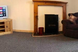 a living room with a fireplace with a couch and a television at Traditional Croft house in Creagorry