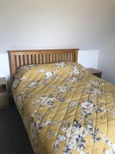 a bed with a yellow comforter with flowers on it at Traditional Croft house in Creagorry