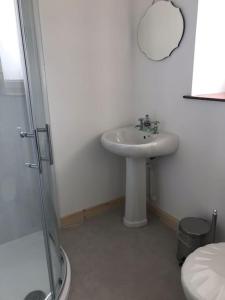 y baño blanco con lavabo y ducha. en Traditional Croft house, en Creagorry