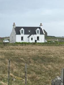 a large white house in the middle of a field at Traditional Croft house in Creagorry