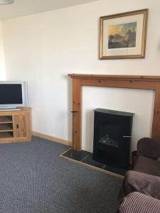 a living room with a fireplace and a tv at Traditional Croft house in Creagorry