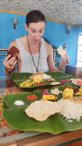 a woman sitting at a table with a plate of food at Beach Paradise Day Cruise Houseboat - VACCINATED STAFF in Alleppey