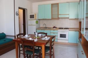 cocina con mesa y sillas y cocina con armarios azules en Mille Bouganville, en Platamona