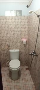 łazienka z toaletą w wyłożonej kafelkami ścianie w obiekcie NEW CORALs w Gili Trawangan