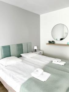 duże łóżko z białą pościelą i lustrem w obiekcie AL-DOM apartamenty Olymp 109 w Kołobrzegu +11 zdjęć