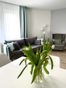 a living room with a vase of flowers on a table at AL-DOM apartamenty Olymp 109 in Kołobrzeg