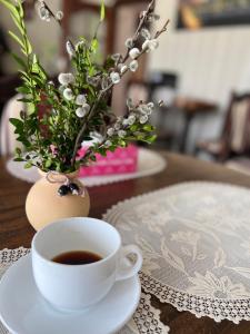 eine Tasse Kaffee und eine Vase mit Blumen auf dem Tisch in der Unterkunft S'Vitt in Schidnyzja