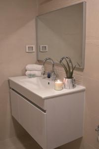 a white bathroom with a sink and a mirror at Beit-sitti in ‘Akko