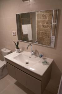a bathroom with a sink and a toilet and a mirror at Beit-sitti in Acre