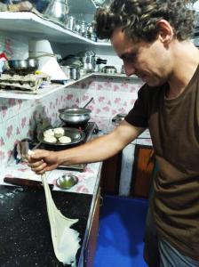 un hombre de pie en una cocina preparando comida en Blackcherry Munnar en Munnar