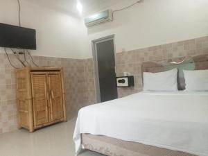 1 dormitorio con 1 cama blanca y TV en NEW CORALs, en Gili Trawangan