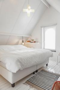 a white bedroom with a white bed and a window at Vakantiehuis Juliette in Diksmuide