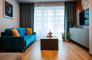 un salon avec un canapé bleu et une table basse dans l'établissement Apartament Turkusowy - basen, sauna, klimatyzacja, à Dziwnów