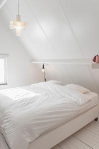 een wit bed in een witte slaapkamer met een plafond bij Vakantiehuis Juliette in Diksmuide