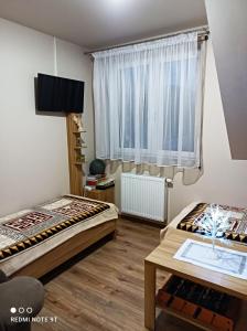 two beds in a room with a window and a table at Apartament Gajówka z ogrodem na wyłączność, Energylandia 35min in Rzyki