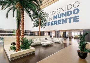 a lobby with palm trees and couches in a building at Ilunion Calas de Conil in Conil de la Frontera