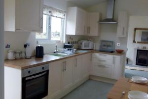 a kitchen with white cabinets and a sink at Coastal Garden Lodge in Preesall