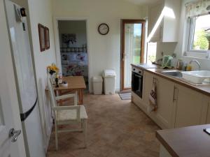 cocina con fregadero y mesa con silla en Coastal Garden Lodge, en Preesall