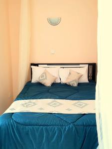 a bed with blue and white sheets and pillows at Eland Accommodations - Ongata Rongai in Ongata Rongai 