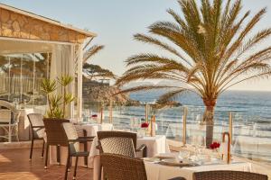 un restaurante con mesas y sillas y vistas al océano en Secrets Mallorca Villamil Resort & Spa - Adults Only (+18) en Paguera