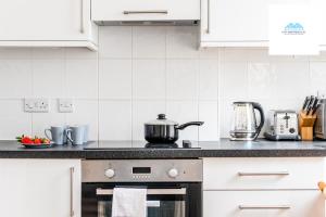 a kitchen with white cabinets and a stove at Charming 1 bed Apartment near Museum in London