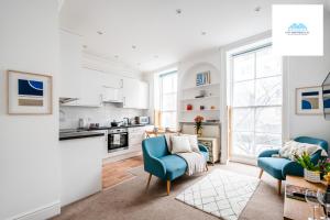 a living room with two blue chairs and a kitchen at Charming 1 bed Apartment near Museum in London