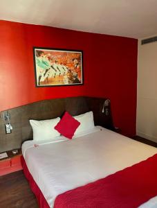 a red bedroom with a bed with a red wall at Hotel Moulin Plaza in Paris