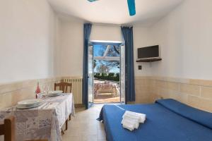 un soggiorno con tavolo e letto blu di Residence La Scogliera by BarbarHouse a Torre Colimena