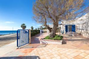 una puerta azul junto a un árbol junto a la playa en Residence La Scogliera by BarbarHouse, en Torre Colimena