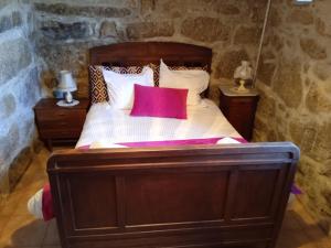 - une chambre avec un lit en bois et un oreiller rouge dans l'établissement Casa da Massada, à Belmonte