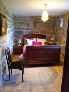 a bedroom with a large bed and a chair at Casa da Massada in Belmonte