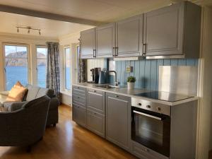 a kitchen with a stove and a couch in a room at Korshamn Rorbuer in Lyngdal